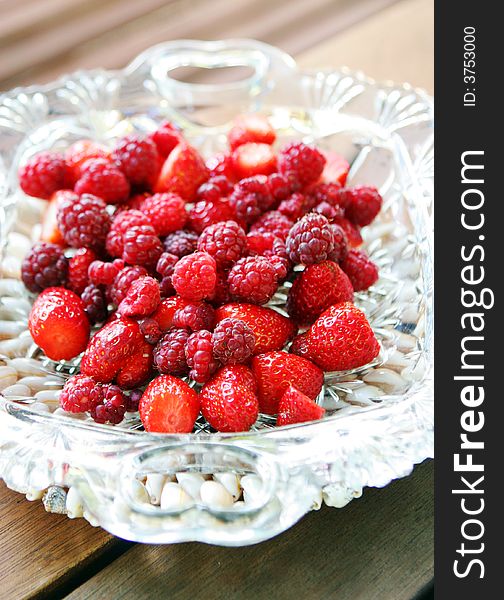 Raspberries and strawberries in a glass bowl.