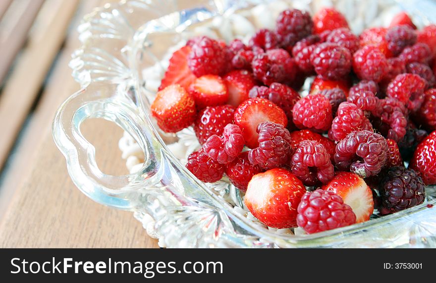 Raspberries and strawberries in a glass bowl.