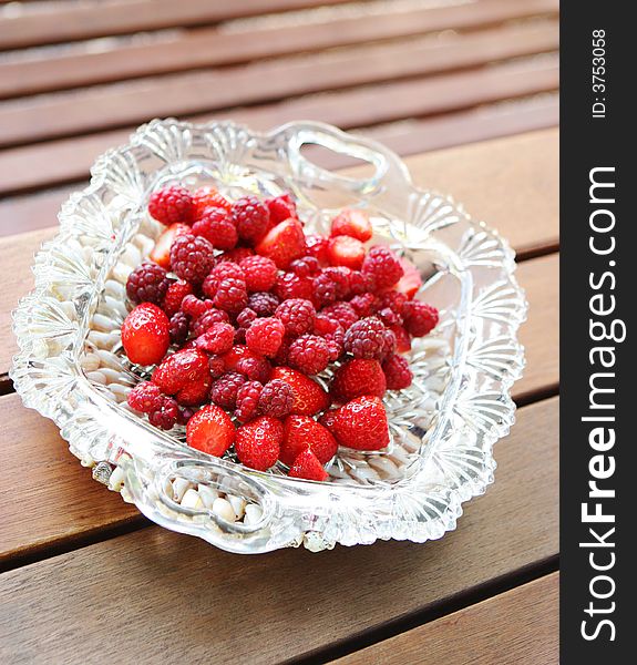 Raspberries and strawberries in a glass bowl.