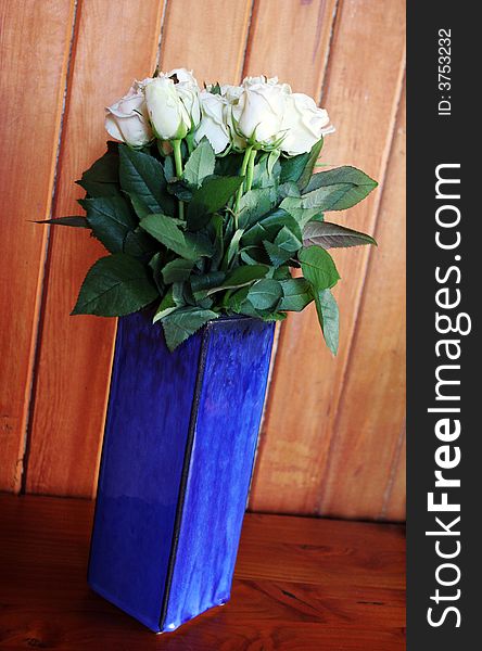 White long stemmed roses in a blue vase.