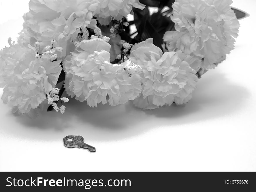 A small key lying close to a bouquet of flowers. A small key lying close to a bouquet of flowers
