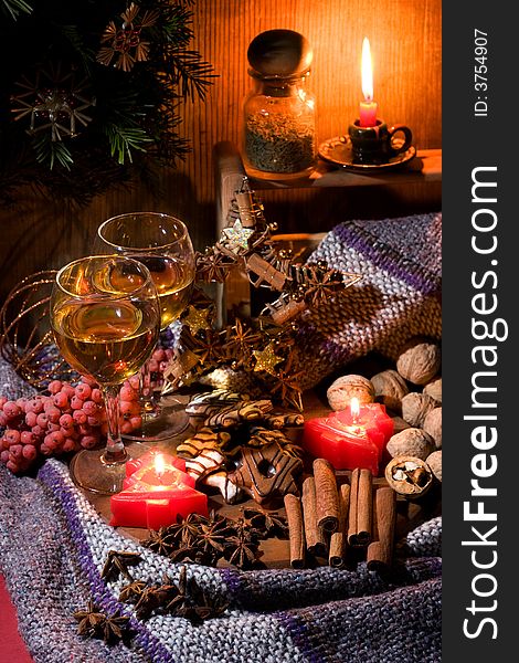 Christmas still-life - candles, cookies, cones, nuts and spices with two glasses of wine