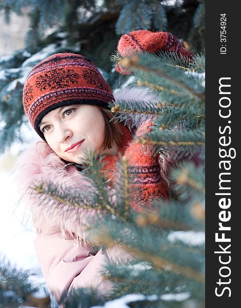 Beautiful girl in hat and mittens in snow-covered evergreens. Beautiful girl in hat and mittens in snow-covered evergreens