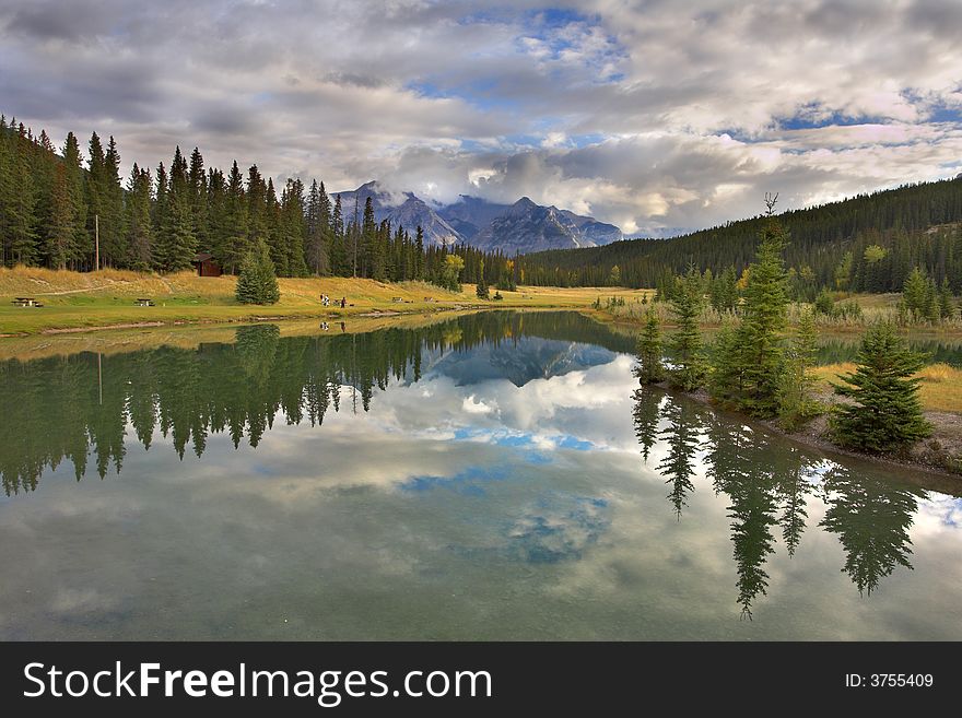 Lake in mountains surrounded by a wood and the cloudy sky above it. Lake in mountains surrounded by a wood and the cloudy sky above it