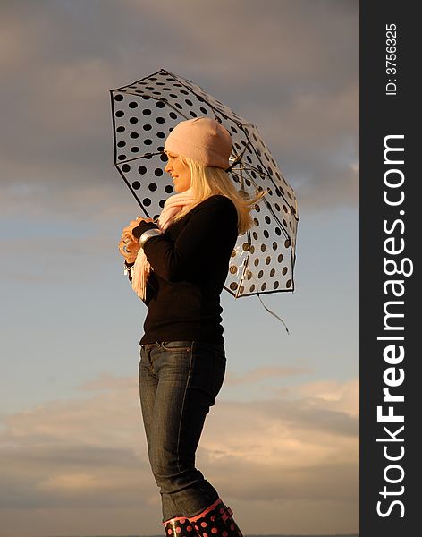 Attractive blonde holding umbrella background of cloudscape. Attractive blonde holding umbrella background of cloudscape.