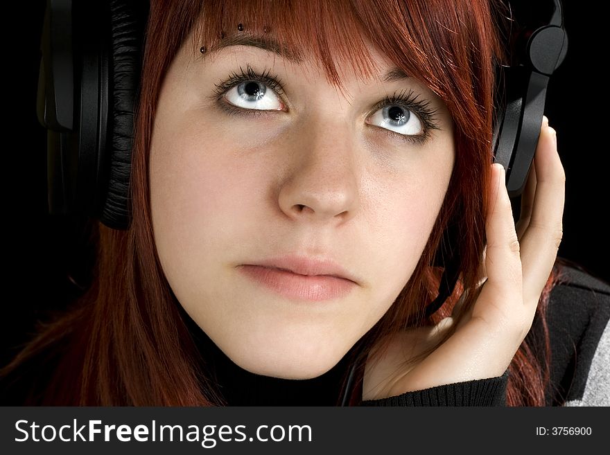 Pensive redhead girl listening to music and enjoying it (looking up, thinking).

Studio shot.