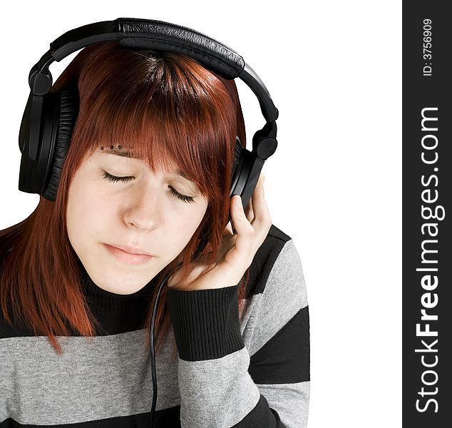 Beautiful redhead girl listening to music on headphones. Studio shot. Beautiful redhead girl listening to music on headphones. Studio shot.