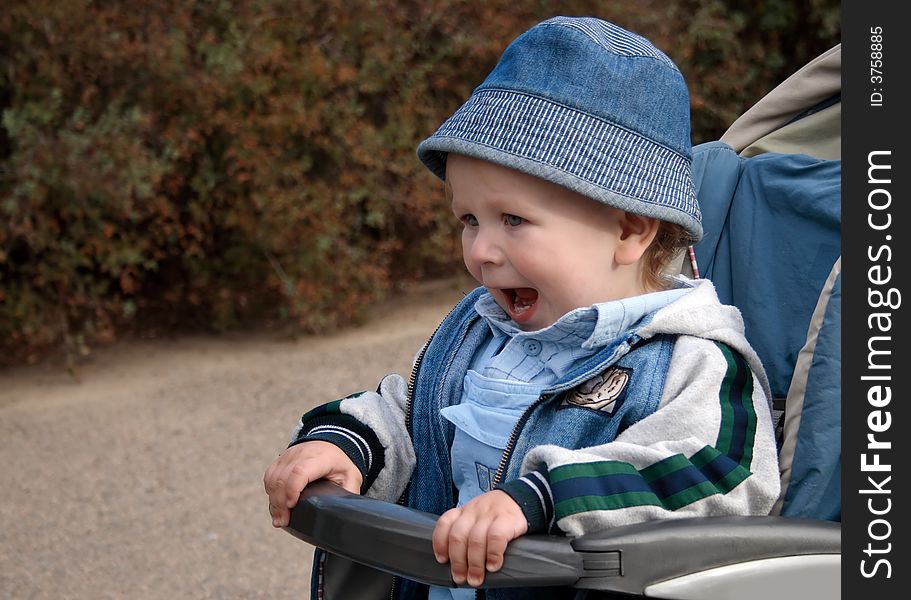 Little boy riding in a baby carriage with mouth open. Little boy riding in a baby carriage with mouth open