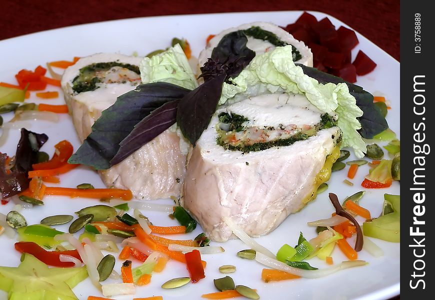 Rolls of chicken meat with greens and vegetables on a white plate. Rolls of chicken meat with greens and vegetables on a white plate