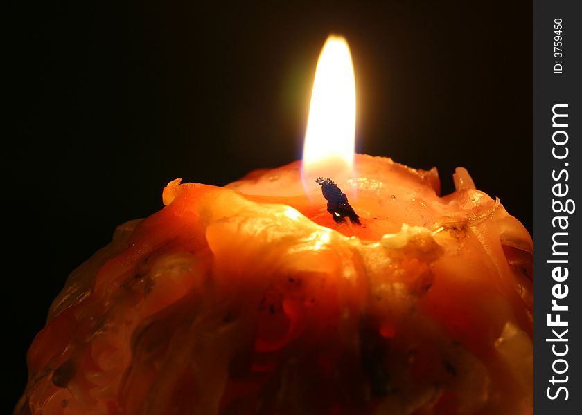 A burning candle in the dark.