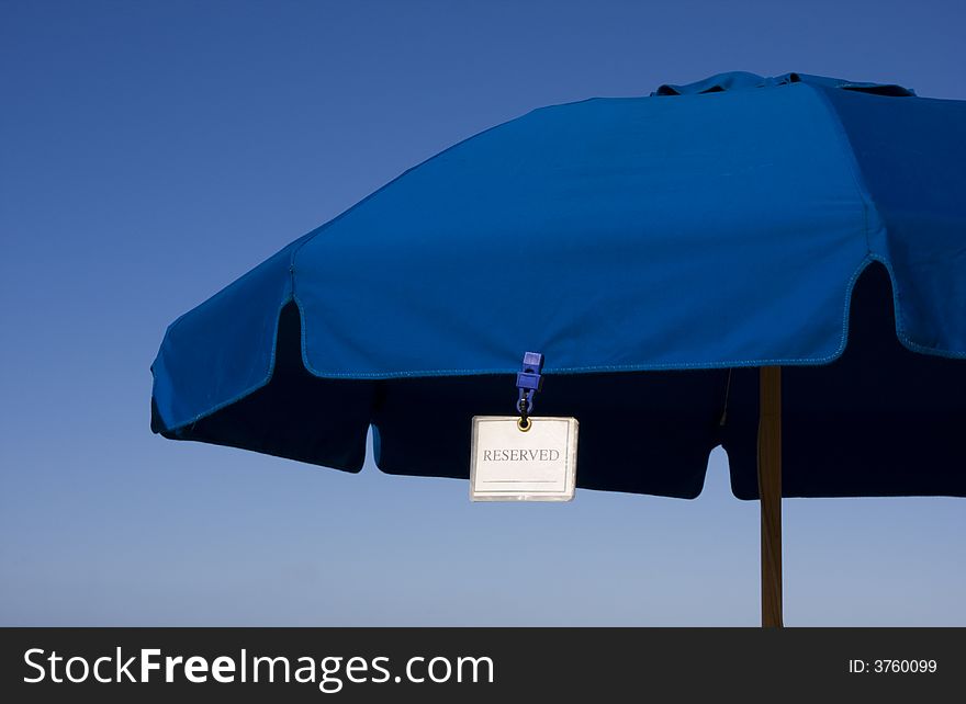 Reserved for you -- a blue beach umbrella under a clear blue sky. Reserved for you -- a blue beach umbrella under a clear blue sky.