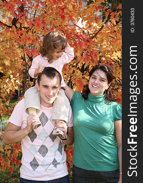 Child on father`s shoulders with mother in the park