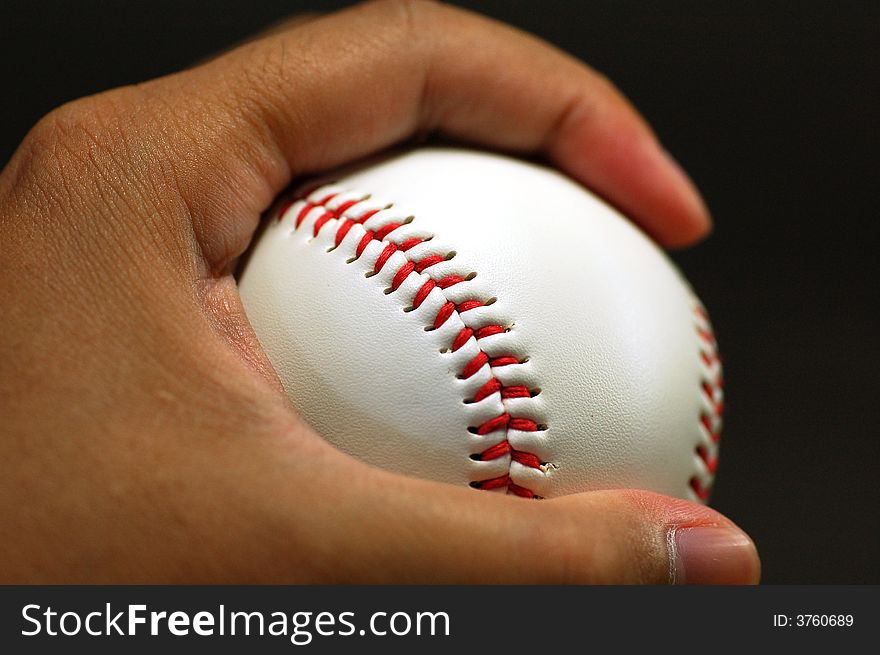 Hand holding baseball, isolated at black background. Hand holding baseball, isolated at black background.