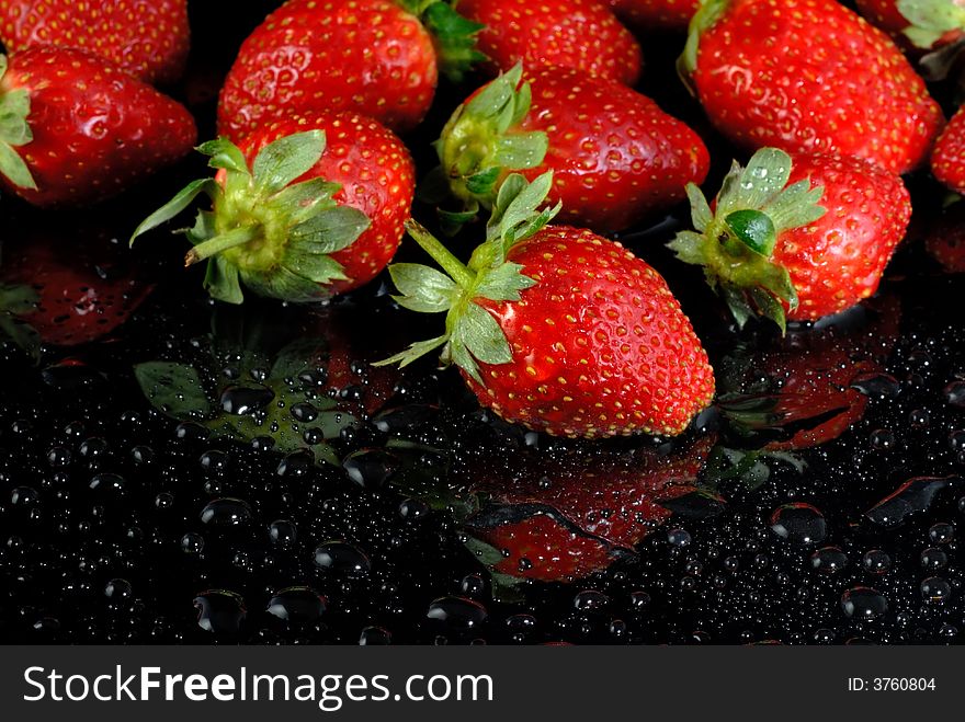 Fresh strawberries with water drops on wet black surface