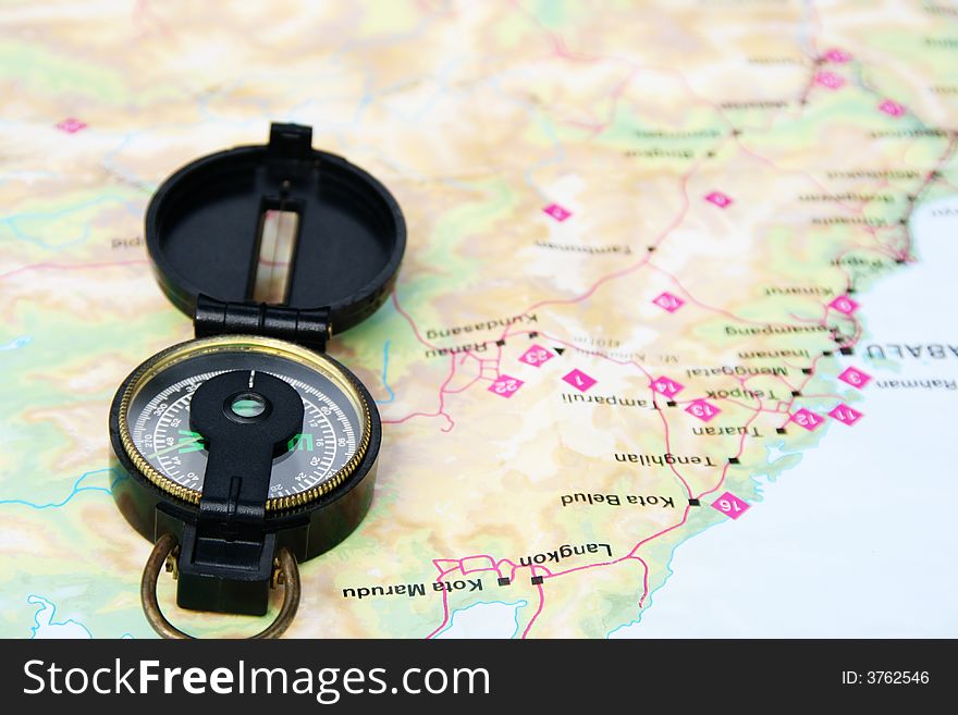 A navigational compass laid on a map.