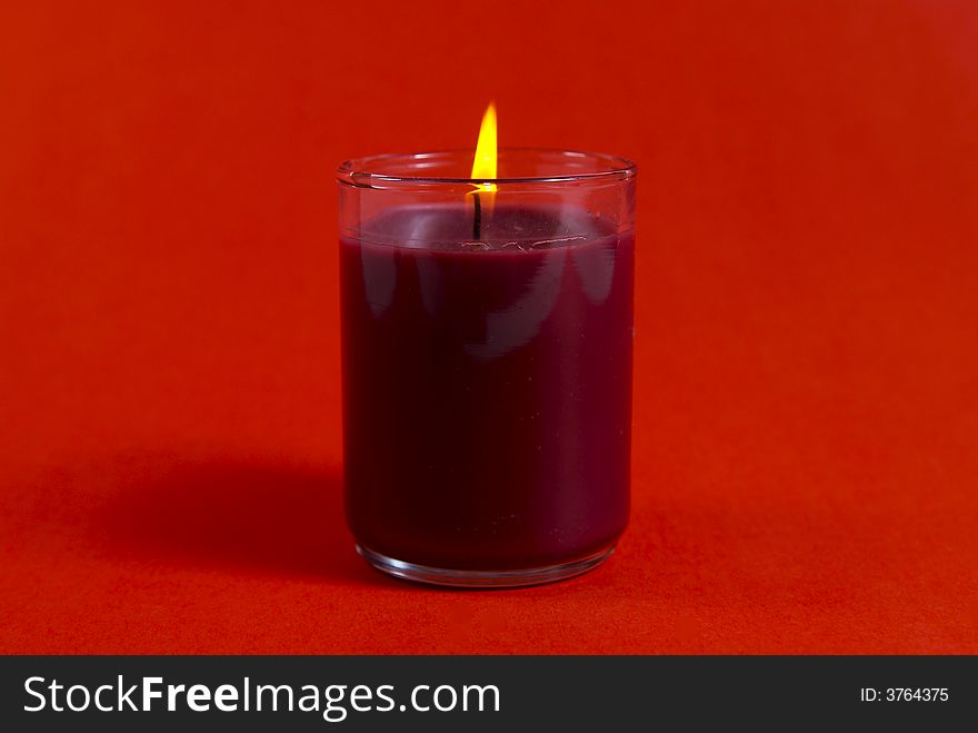 A small Christmas candle shot against a red background.