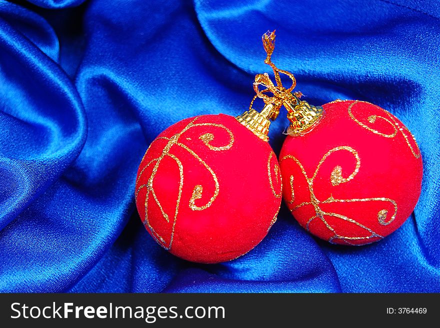 Two red Christmas balls on blue satin. Two red Christmas balls on blue satin