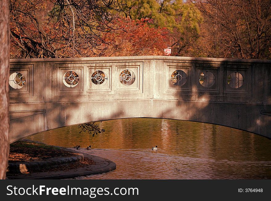 Gray stone bridge across golden autumn pond. Gray stone bridge across golden autumn pond