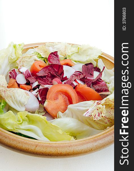 A closeup of a typical italian salad, prepared in a bowl, with lettuce, radicchio, tomato, radish, tropea onions and green endive. A closeup of a typical italian salad, prepared in a bowl, with lettuce, radicchio, tomato, radish, tropea onions and green endive