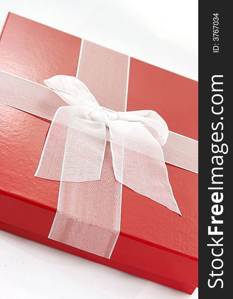 A red box and white ribbon holiday present. A red box and white ribbon holiday present