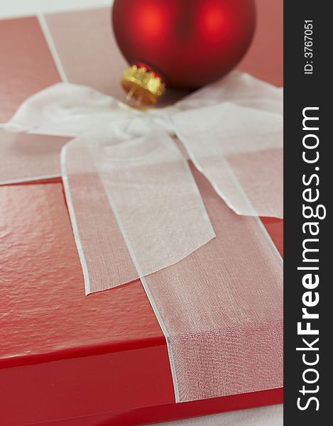 A red box and white ribbon holiday present. A red box and white ribbon holiday present