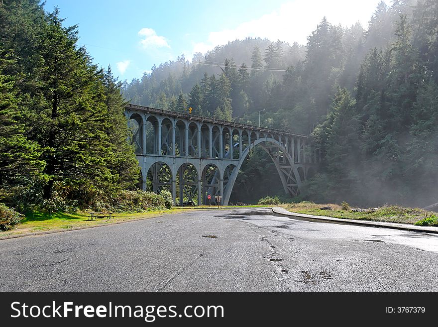 Old railroad bridge over modern paved road as the mist and fog burns off. Old railroad bridge over modern paved road as the mist and fog burns off