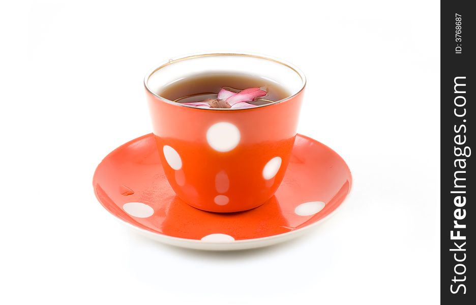 A red punctated saucer and cup with tea adorned with flower isolated on white. A red punctated saucer and cup with tea adorned with flower isolated on white