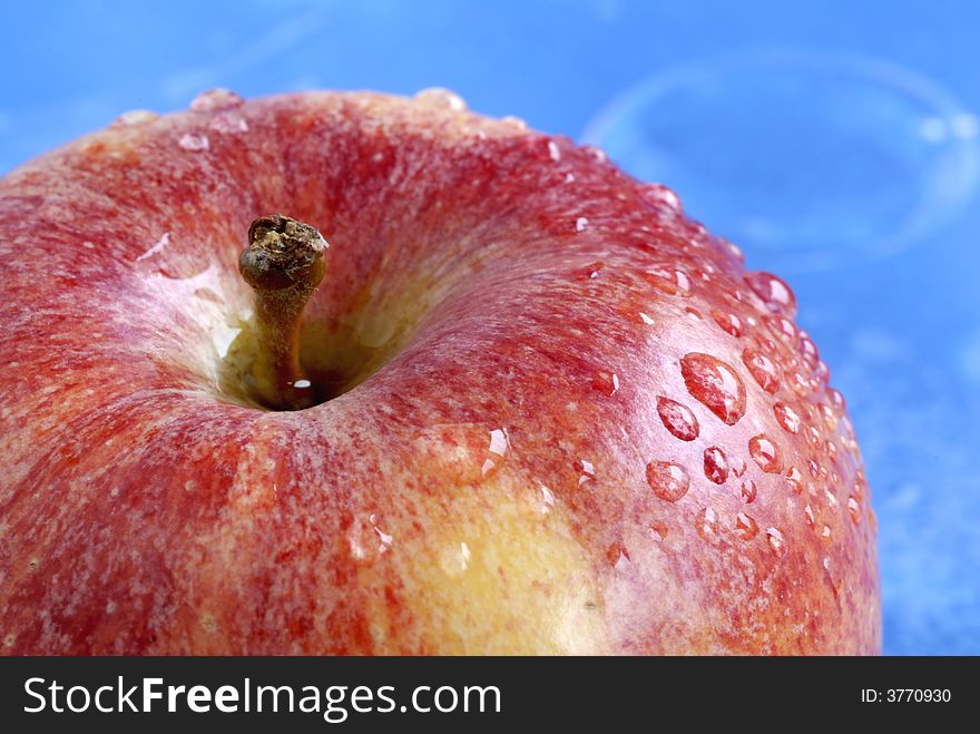 Water drops on apple against blue background