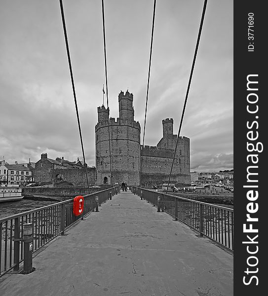 A view across the bridge to Caernarfon Castle, in black and white with red detail