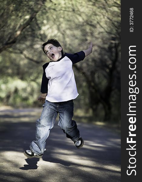 Young boy on a tree-lined path jumps in the air. Young boy on a tree-lined path jumps in the air.