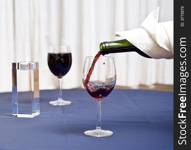 Filling a glass with red wine (restaurant scene). Filling a glass with red wine (restaurant scene).