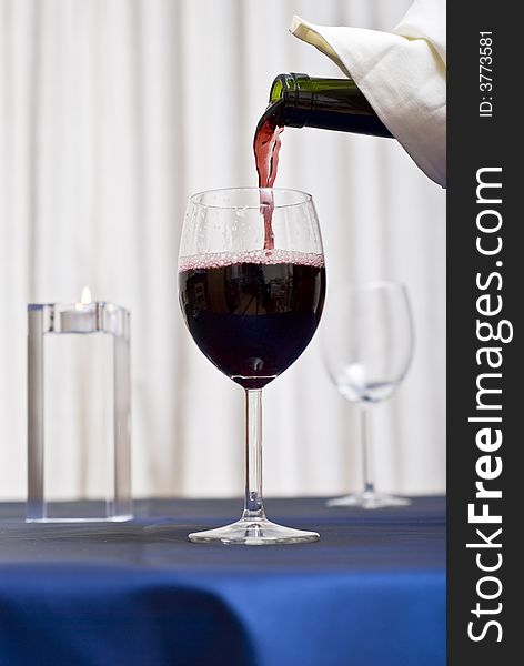 Filling a glass with red wine (restaurant scene). Filling a glass with red wine (restaurant scene).
