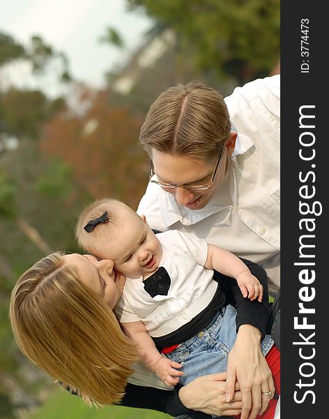 Attractive young parents and their little baby daughter posing for a portrait at the park. Attractive young parents and their little baby daughter posing for a portrait at the park