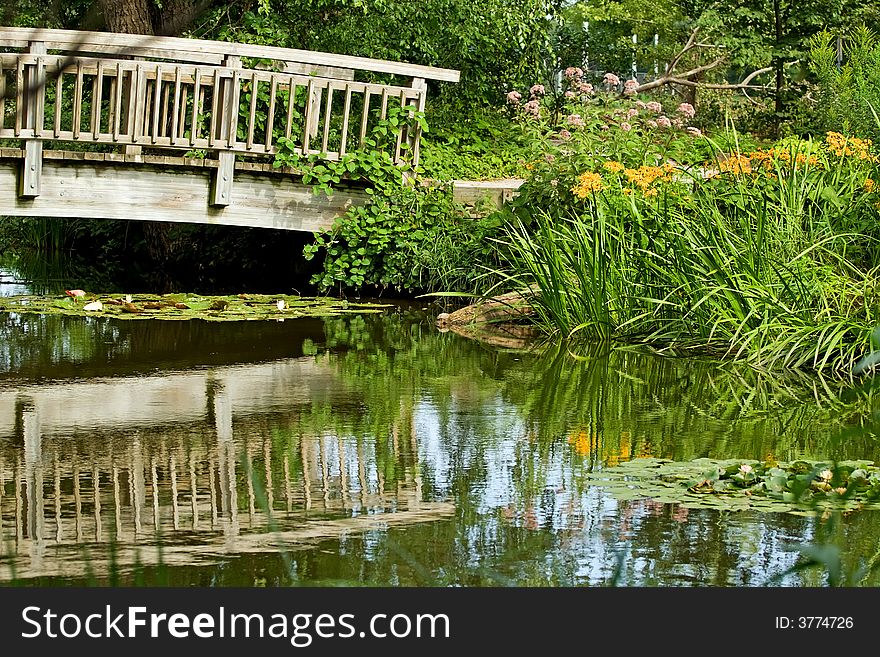 Reflection of flowers and wooden bridge in pond. Reflection of flowers and wooden bridge in pond