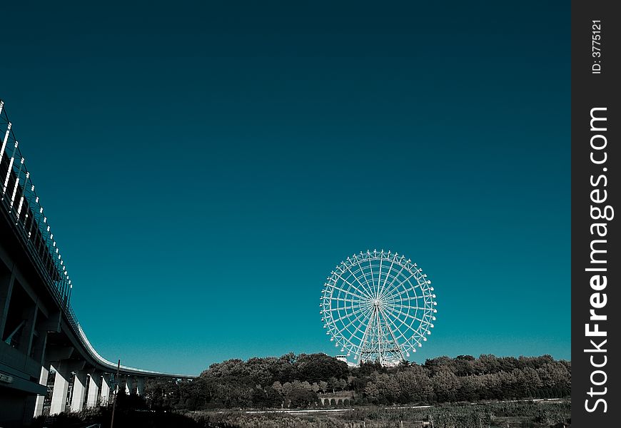 Amusements wheel in the middle of forest with tilted road to it