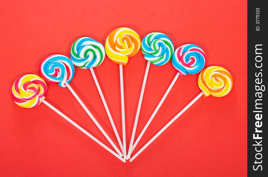 Twirl lollipop candies over a red background