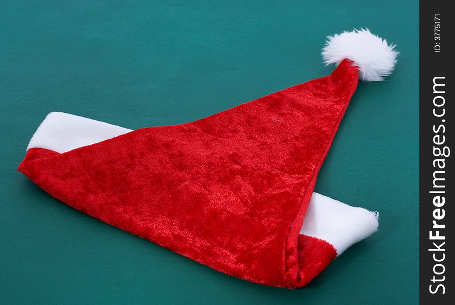 A red christmas hat over a green background