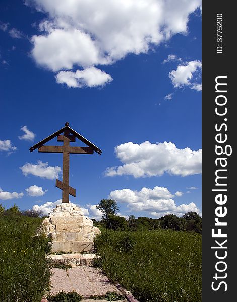 Orthodox cross over meadow and blue sky at oracle - spring named White well. Orthodox cross over meadow and blue sky at oracle - spring named White well