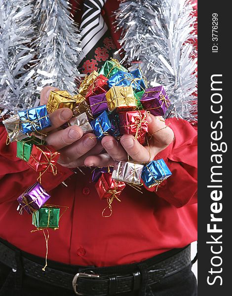 Man in a red shirt with a Christmas tie handing a small presents.