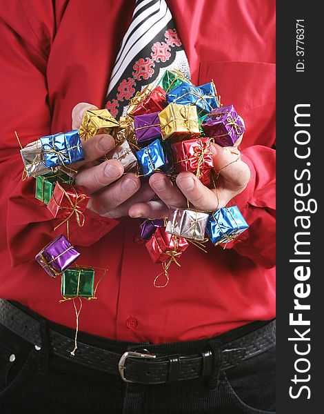 Man in a red shirt with a Christmas tie handing a small presents.