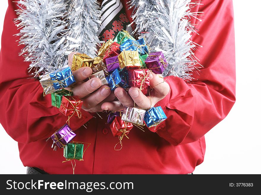 Man in a red shirt with a Christmas tie handing a small presents.