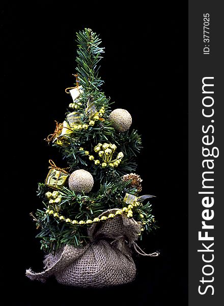 Cute little christmastree with ornaments and presents isolated on black