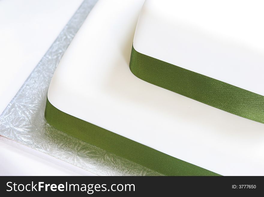 Fruit cake iced and decorated with green ribbon.