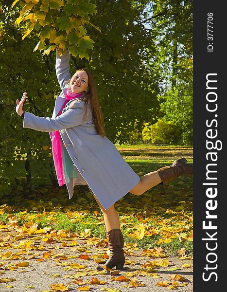 The cheerful beautiful girl in autumn park