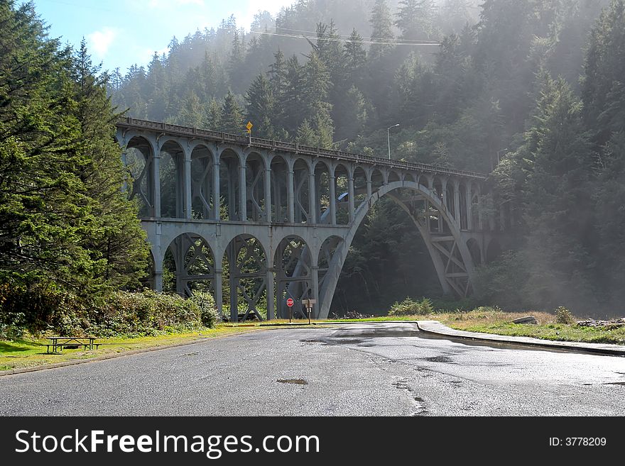 Old railroad bridge over modern paved road as the mist and fog burns off. Old railroad bridge over modern paved road as the mist and fog burns off