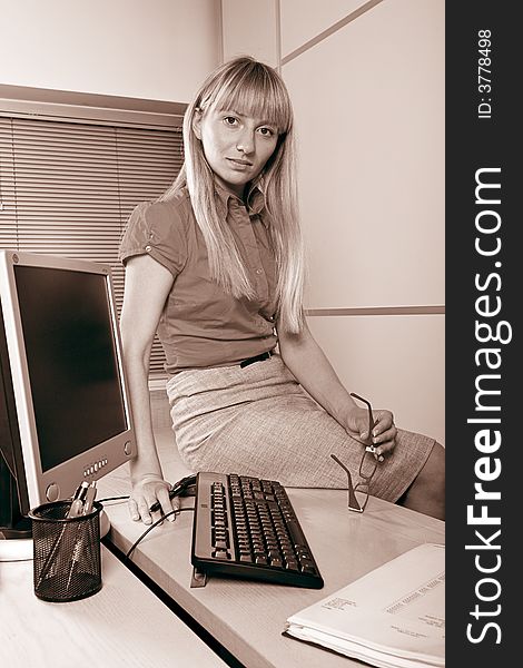 Woman sitting on the desk in front of computer. Woman sitting on the desk in front of computer