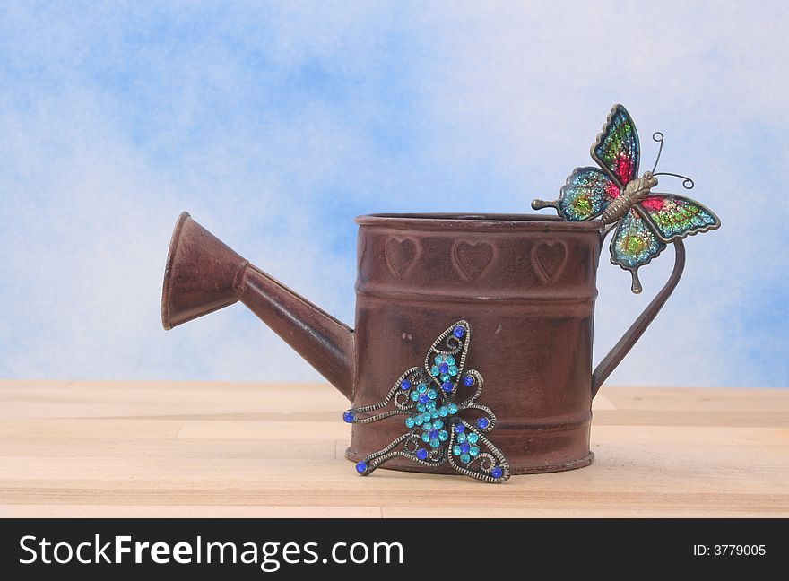 Metal Watering Can on Blue Sky Background With Betterflies. Metal Watering Can on Blue Sky Background With Betterflies