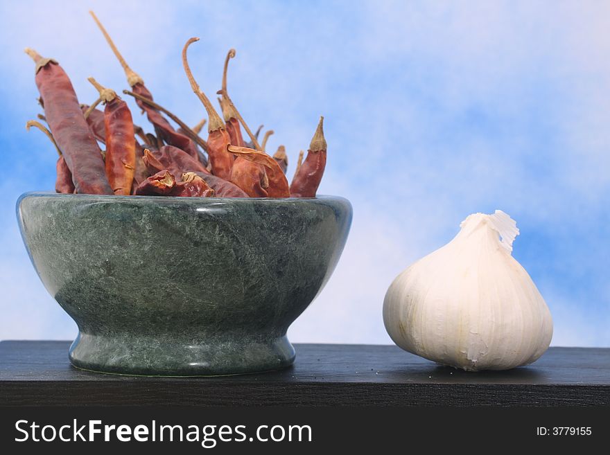 Peppers and Garlic on Black Table With Blue Sky Background