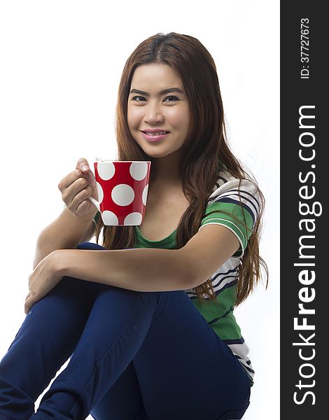 Portrait Of Asian Young Woman Sitting Of The Floor And Holding Coffee Cup Isolated