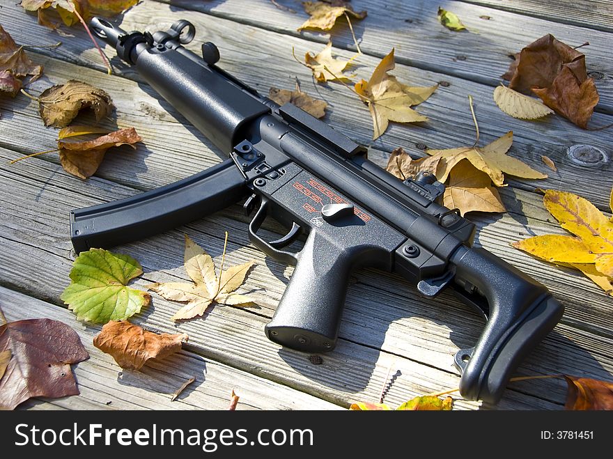 Picture of a sub machine gun surrounded by leaves. Picture of a sub machine gun surrounded by leaves